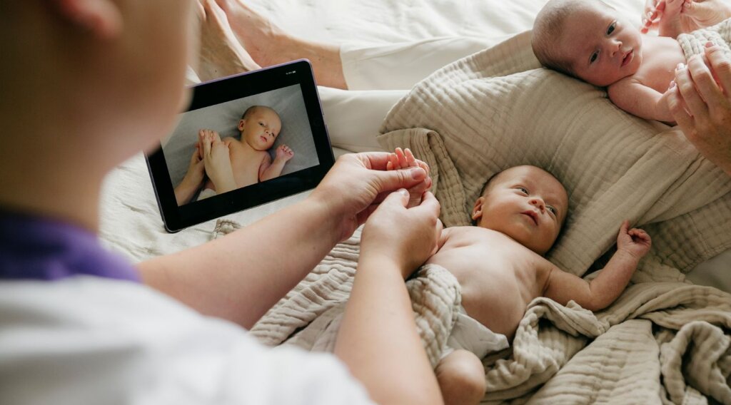 Tweelingen krijgen babymassage, kraamverzorgende Naviva doet het voor met behulp van een instructievideo over babymassage uit de Nieuw Leven App.