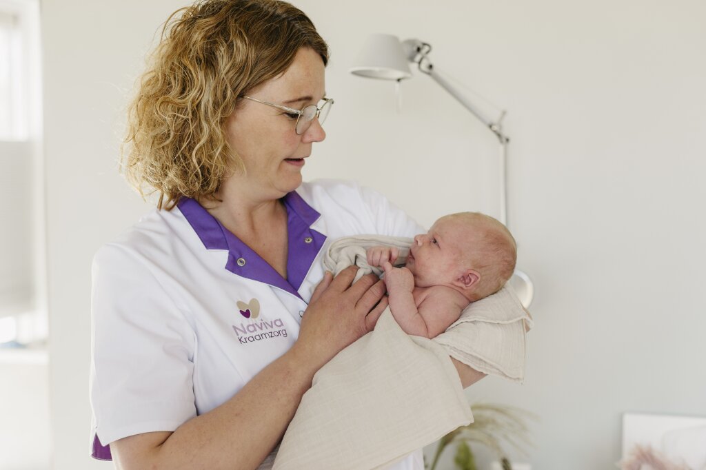 Kraamverzorgende van Naviva kraamzorg met pasgeboren baby.
