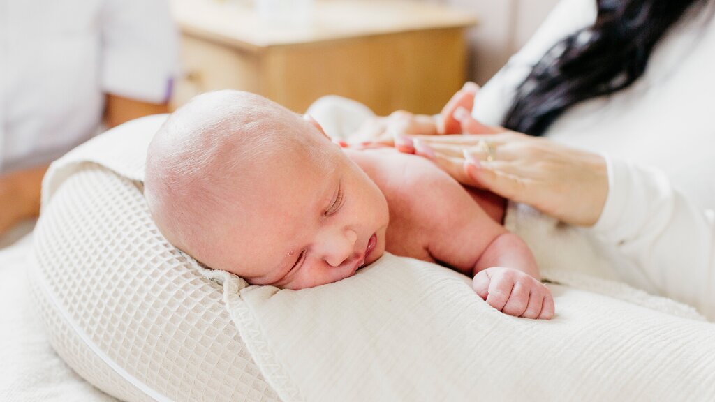Moeder masseert baby tijdens kraamweek. Naviva kraamzorg.